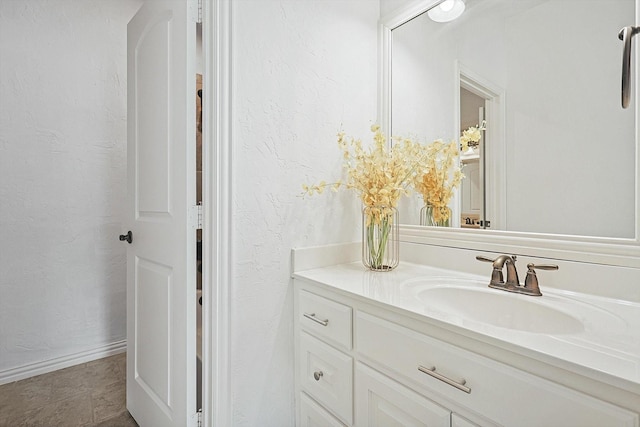 bathroom featuring vanity, a textured wall, and baseboards