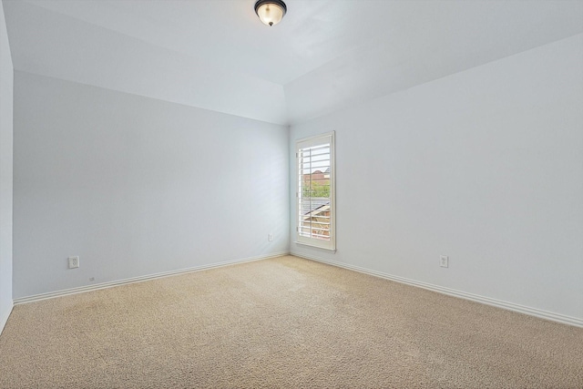 empty room featuring vaulted ceiling, baseboards, and light carpet