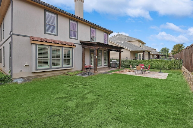 rear view of house featuring stucco siding, a fenced backyard, a yard, a chimney, and a patio area