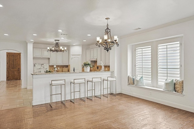 kitchen with decorative backsplash, crown molding, a peninsula, and visible vents