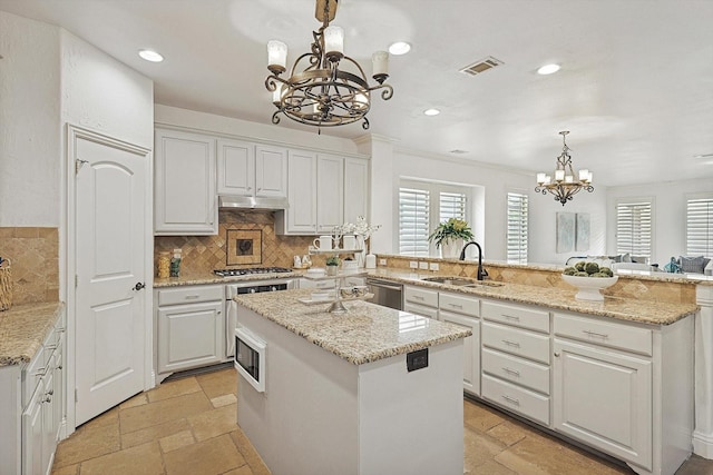 kitchen featuring stone tile floors, visible vents, a sink, appliances with stainless steel finishes, and a notable chandelier