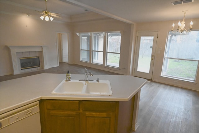 kitchen with sink, light wood-type flooring, white dishwasher, pendant lighting, and a fireplace