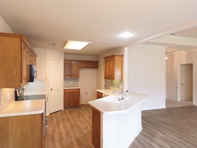 kitchen with sink, kitchen peninsula, stainless steel appliances, crown molding, and light hardwood / wood-style flooring