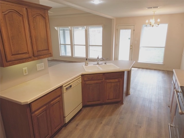 kitchen with white dishwasher, sink, decorative light fixtures, and plenty of natural light