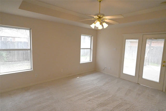 carpeted spare room with ceiling fan and a raised ceiling