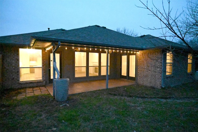 back house at dusk with central air condition unit and a patio area