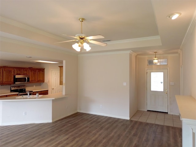 kitchen with crown molding, appliances with stainless steel finishes, a tray ceiling, ceiling fan, and hardwood / wood-style floors