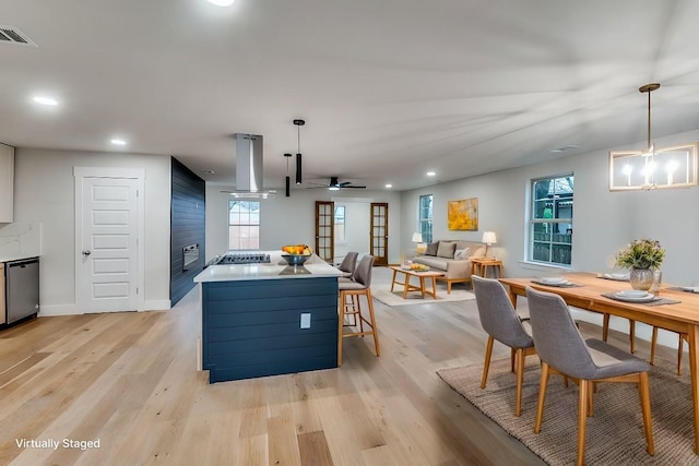 kitchen featuring pendant lighting, stainless steel appliances, island range hood, and light wood-type flooring