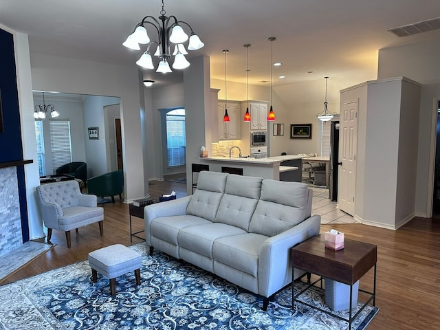 living room featuring hardwood / wood-style flooring, vaulted ceiling, sink, and a notable chandelier