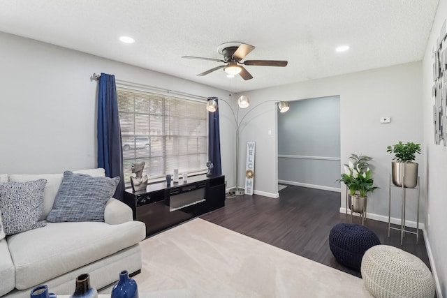 living room featuring ceiling fan, dark wood-type flooring, and a textured ceiling