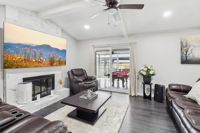 living room with dark wood-type flooring, ceiling fan, a premium fireplace, and lofted ceiling with beams