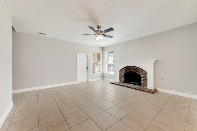 unfurnished living room with a brick fireplace, light tile patterned floors, and ceiling fan