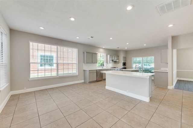 kitchen featuring light tile patterned floors, sink, gray cabinets, a kitchen island, and stainless steel dishwasher