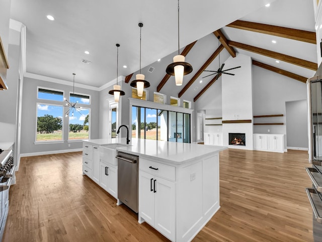 kitchen featuring decorative light fixtures, a center island with sink, light wood-type flooring, dishwasher, and white cabinets