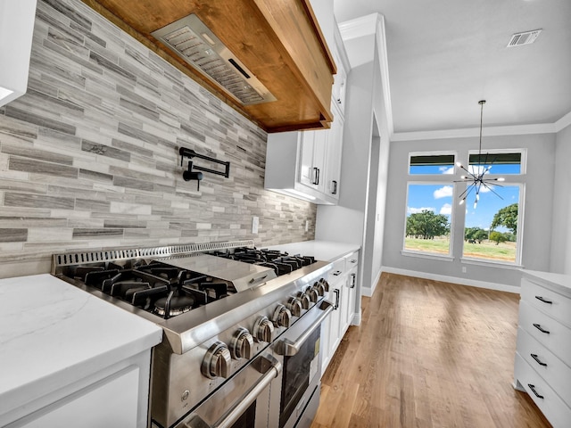 kitchen featuring white cabinetry, light stone counters, decorative light fixtures, double oven range, and backsplash