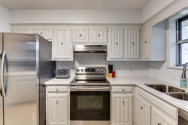 kitchen with sink, backsplash, stainless steel appliances, and white cabinets