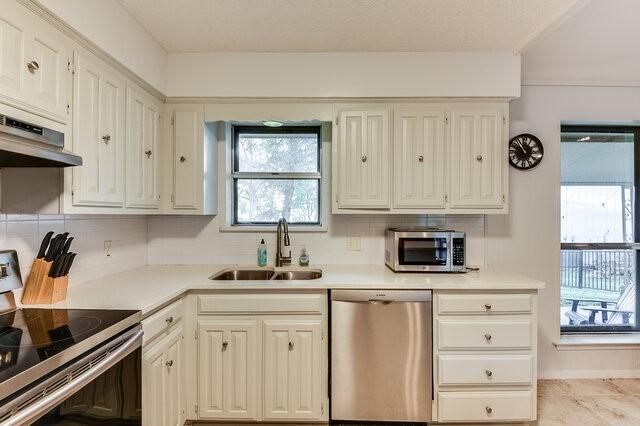 kitchen with tasteful backsplash, appliances with stainless steel finishes, and sink