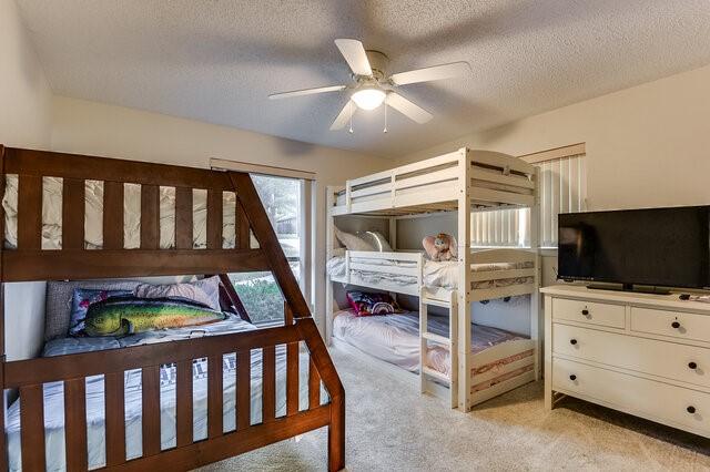 carpeted bedroom featuring ceiling fan and a textured ceiling