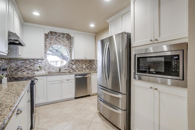 kitchen with light tile patterned flooring, sink, white cabinets, stainless steel appliances, and light stone countertops