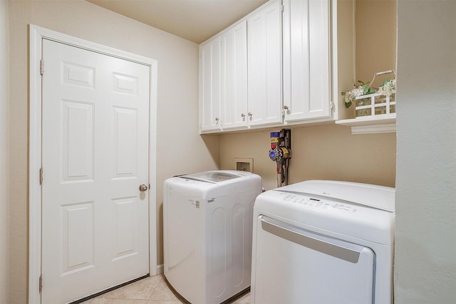 washroom with cabinets, washer and dryer, and light tile patterned floors