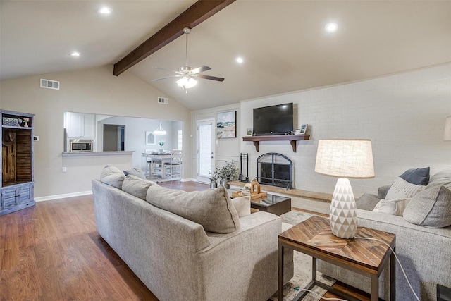 living room featuring high vaulted ceiling, dark hardwood / wood-style flooring, ceiling fan, a brick fireplace, and beam ceiling