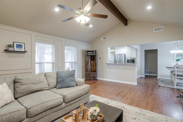 living room featuring hardwood / wood-style flooring, ceiling fan, and lofted ceiling with beams