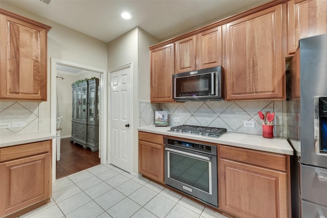 kitchen featuring tasteful backsplash, light tile patterned floors, and stainless steel appliances