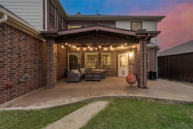 back house at dusk featuring outdoor lounge area and a patio area