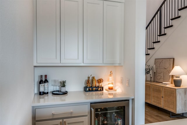 bar featuring wine cooler, white cabinetry, and hardwood / wood-style floors