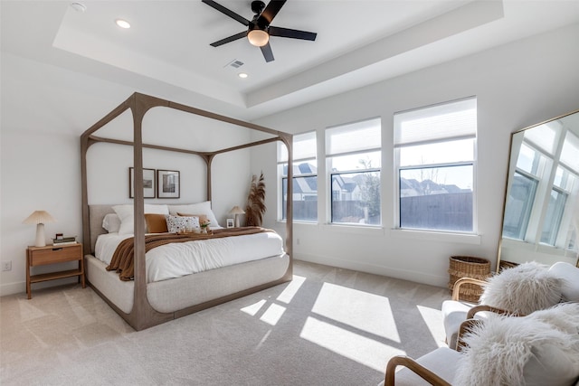 carpeted bedroom featuring a raised ceiling and ceiling fan