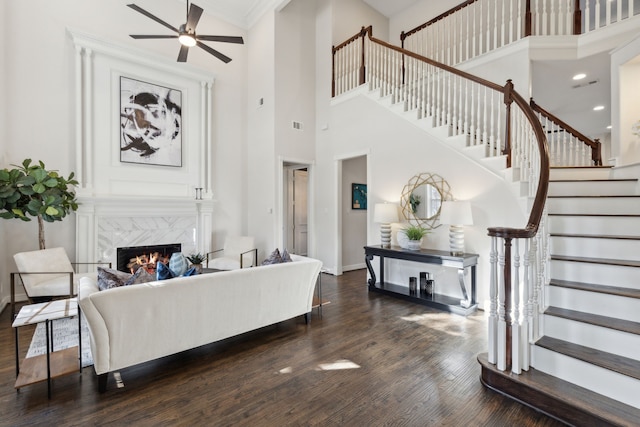 living room with ceiling fan, dark hardwood / wood-style floors, crown molding, and a fireplace