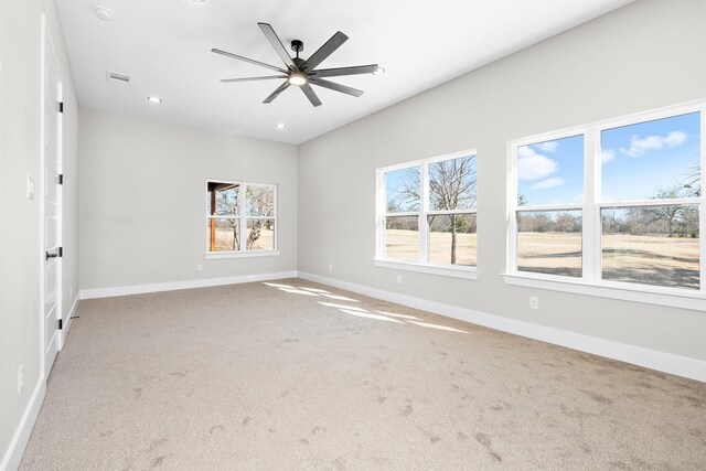 empty room with ceiling fan, carpet floors, and a wealth of natural light