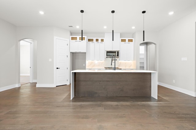 kitchen with a center island with sink, dark hardwood / wood-style floors, pendant lighting, and white cabinets