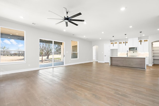 unfurnished living room with dark wood-type flooring, sink, and ceiling fan