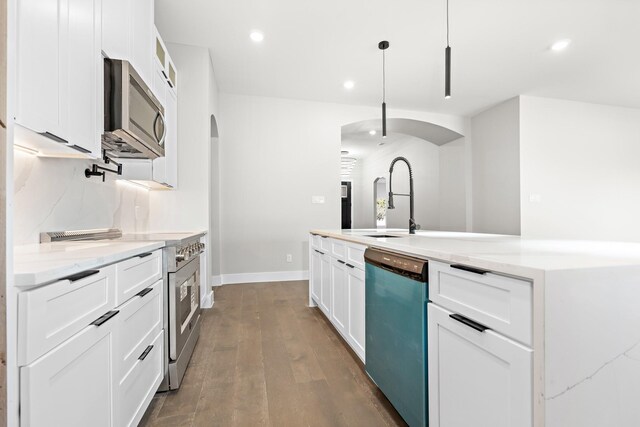 kitchen featuring hanging light fixtures, stainless steel appliances, and white cabinets