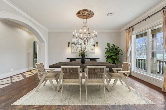 dining space with hardwood / wood-style flooring, crown molding, and a chandelier