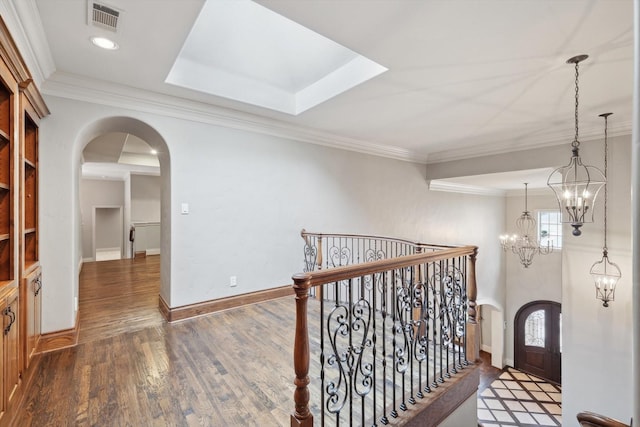 hallway with crown molding, dark wood-type flooring, and a chandelier