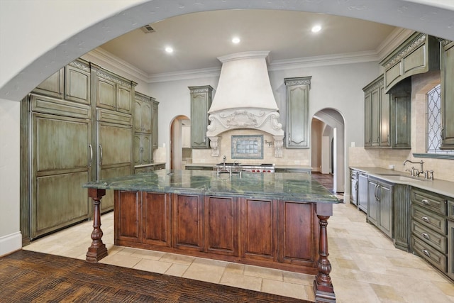 kitchen with a kitchen island with sink, custom exhaust hood, and dark stone countertops