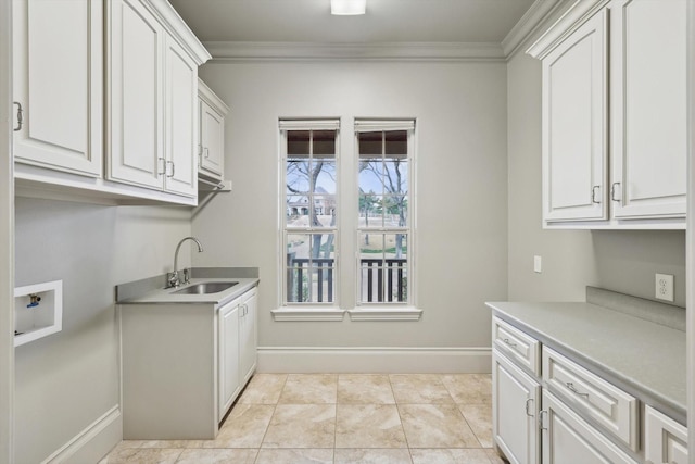 laundry room featuring white cabinetry, ornamental molding, and sink