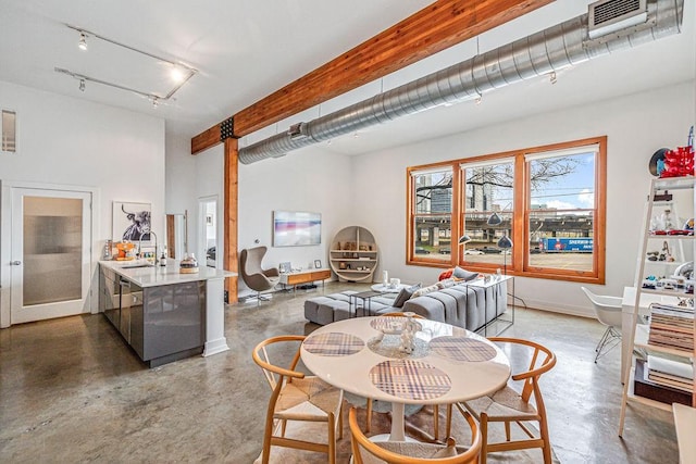 dining space featuring concrete floors, visible vents, track lighting, and beamed ceiling