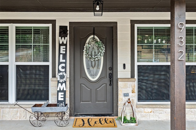 entrance to property with a porch and stone siding