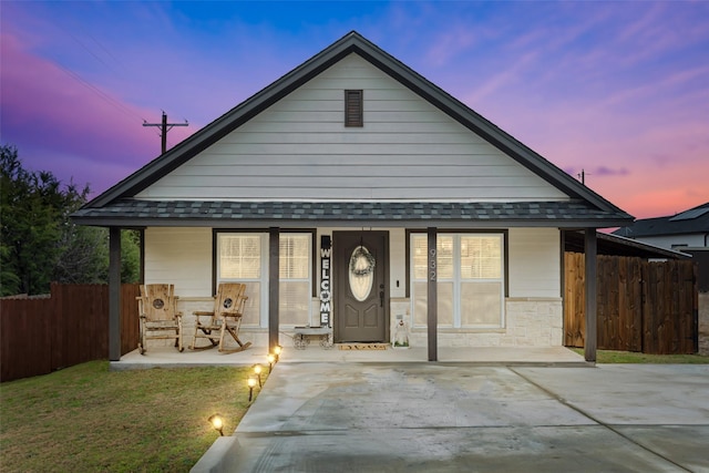 view of front of home with a porch, fence, and a shingled roof