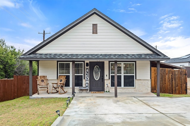 view of front of house featuring roof with shingles, a porch, and fence