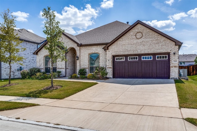 french country inspired facade with a garage, central air condition unit, and a front lawn