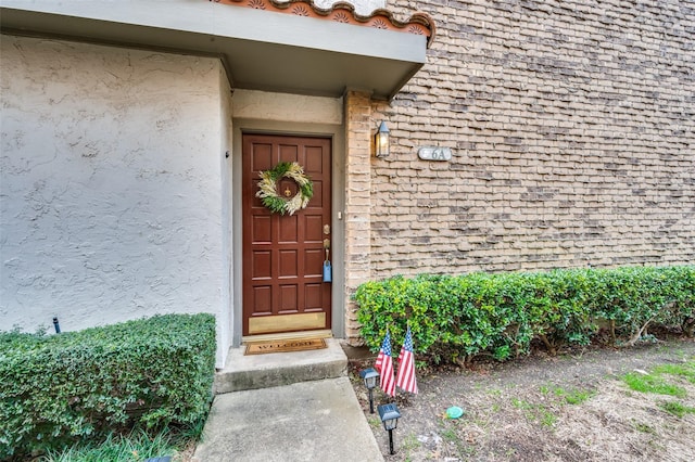 doorway to property with roof with shingles and stucco siding