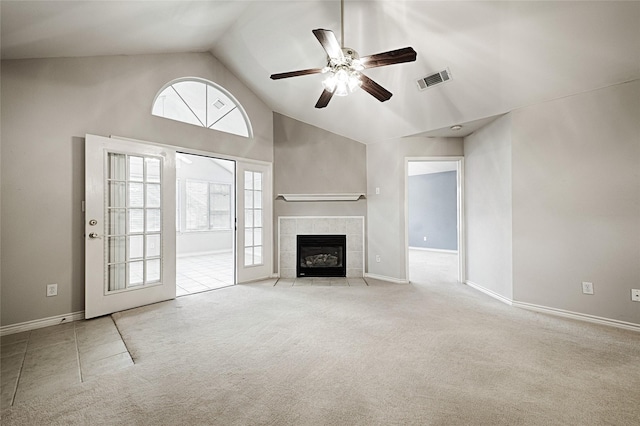 unfurnished living room featuring ceiling fan, a tiled fireplace, high vaulted ceiling, and light carpet