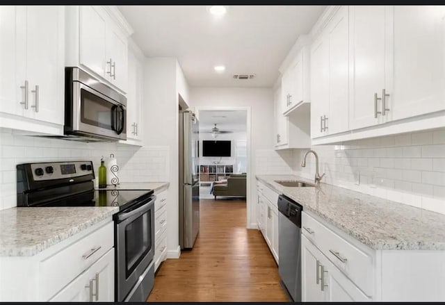 4217 Winfield Ave, Fort Worth, TX 76109 - kitchen featuring stainless steel appliances, a sink, light wood-type flooring, white cabinets, and backsplash