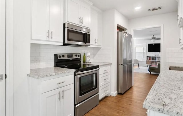 4217 Winfield Ave, Fort Worth, TX 76109 - kitchen with appliances with stainless steel finishes, a ceiling fan, white cabinets, light wood finished floors, and tasteful backsplash