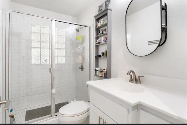 bathroom featuring vanity, a shower with door, and toilet