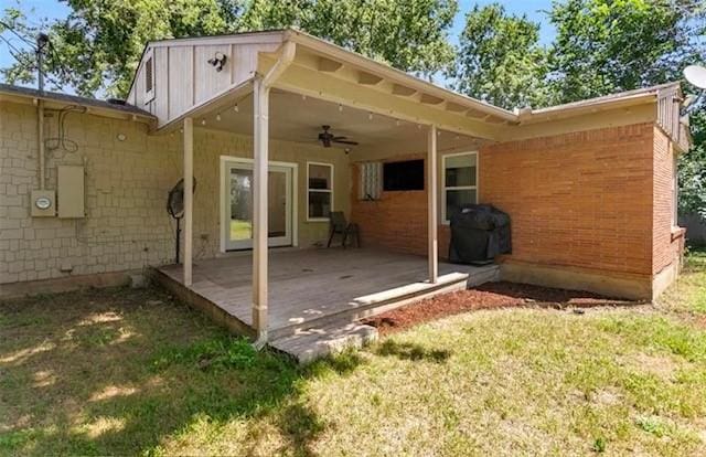 back of property with a wooden deck, ceiling fan, and a lawn